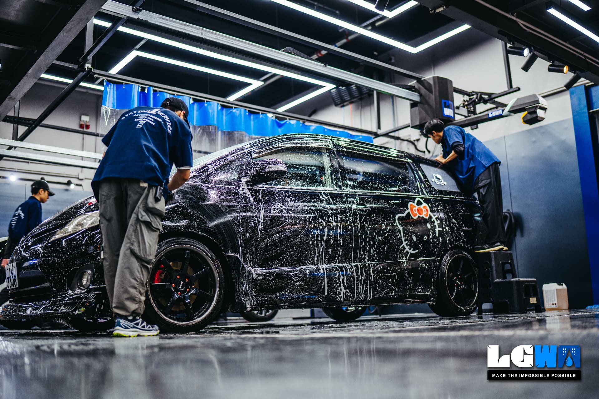 Lets Get Wash 室內工位內，工作人員以白色泡沫手洗一台黑色房車的實拍照